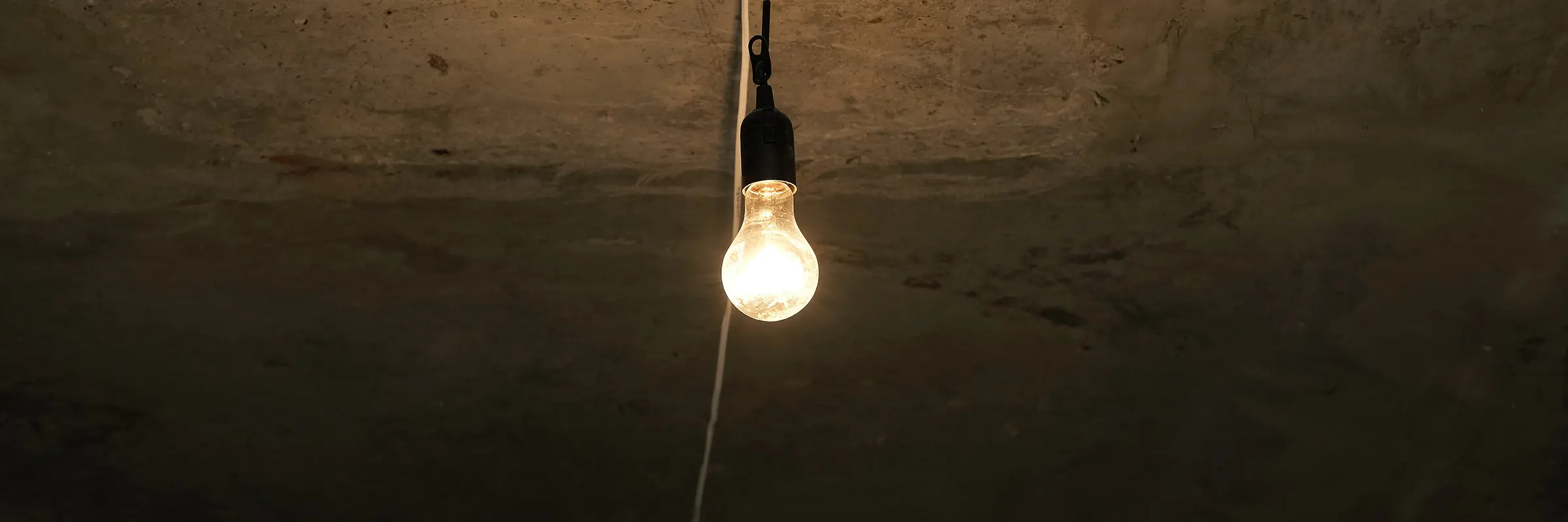 En ensam glödlampa hänger från ett betongtak
